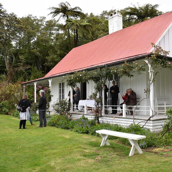 People gather on the lawn and veranda of Hurwoth Cottage after enjoying a tour.