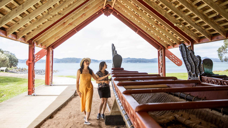 Two women looking at the waka in the wharewaka at Waitangi Treaty Grounds