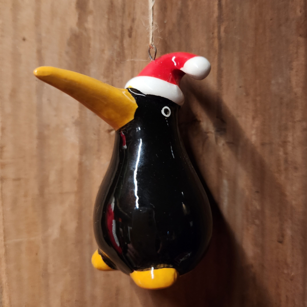 A hanging decoration of a black kiwi in a red and white Christmas hat.