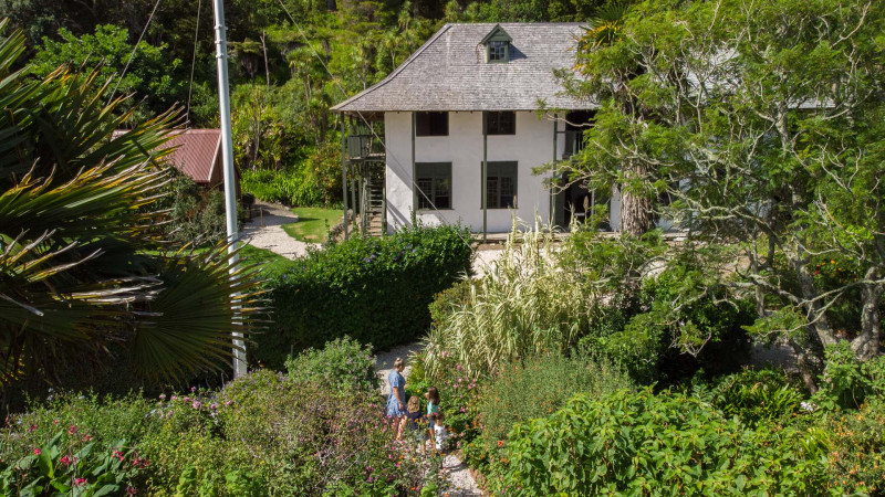 Aerial view of a mother and three children walk through the garden up to the printery building