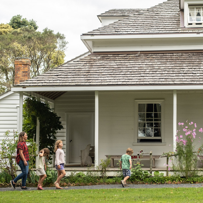 A mother and three children walk past the mission house at Te Waimate Mission